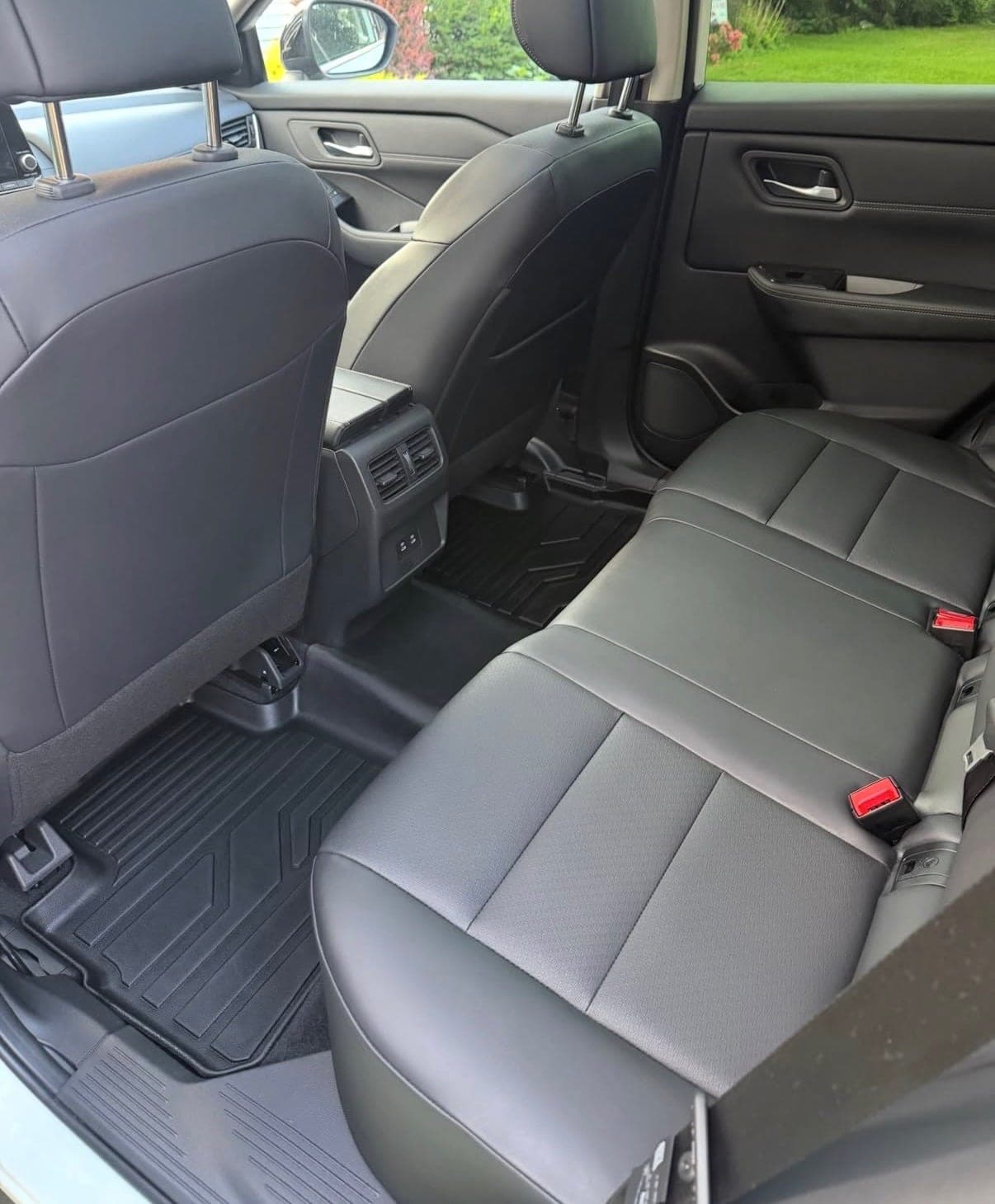 The same rear bench seat after detailing, the leather clean and an even black, with clean floor mats behind it